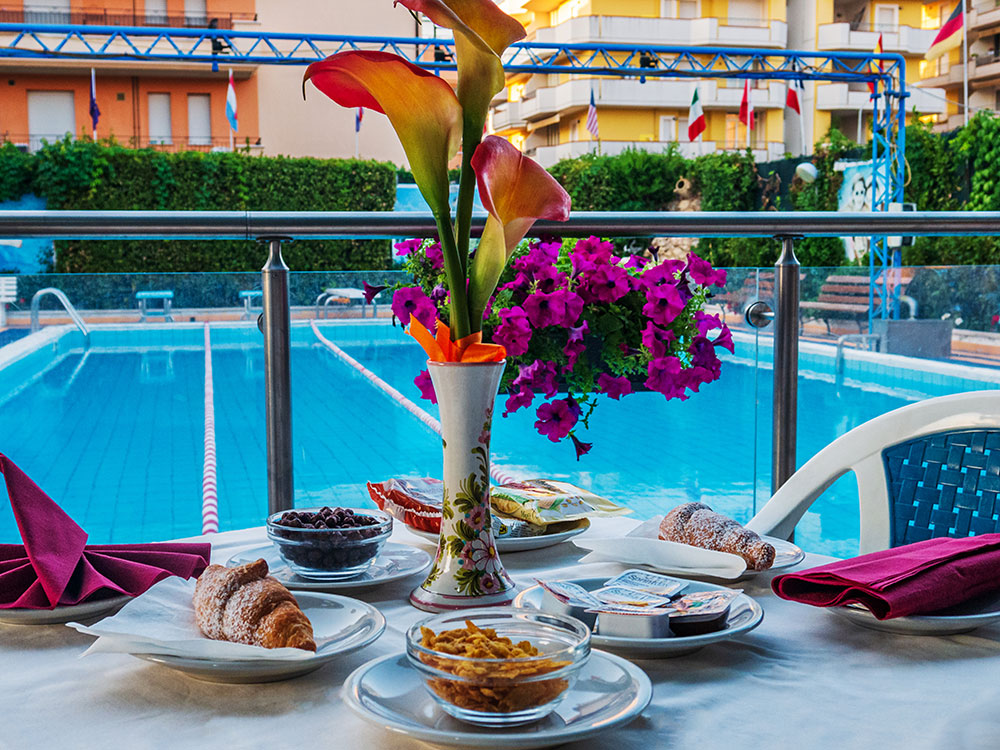 tavolo colazione in piscina L’Hotel Tassoni è un hotel fronte mare sul lungomare di Alba Adriatica 3 stelle con piscina, minicub e junior club per le vacanze delle famiglie con bambini al mare dell'Abruzzo