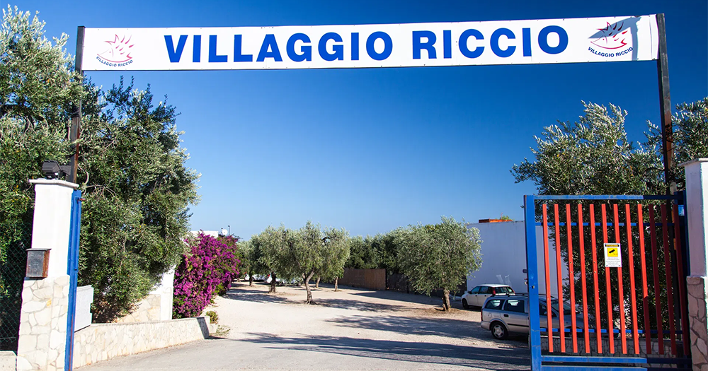 entrata villaggio riccio Il Villaggio Riccio è un villaggio ideale per le vacanze delle famiglie con bambini a Mattinata, sul mare del Gargano a soli 30 metri dalla spiaggia con campi sportivi, bar, ristorante, parco giochi per i bambini.